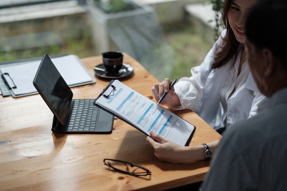 Female healthcare provider helping patient fill out form.