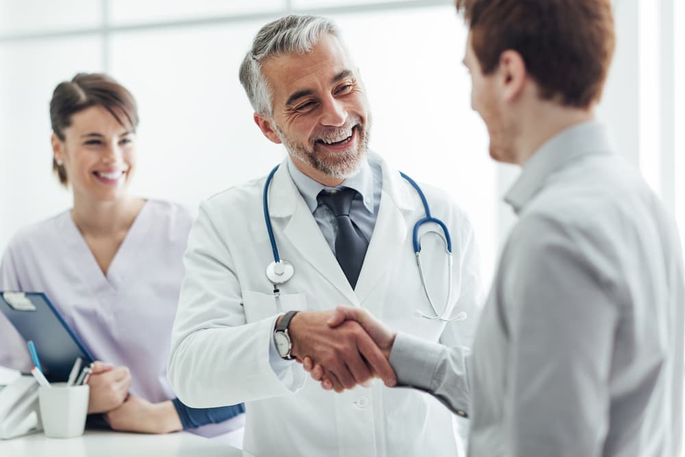 Smiling doctor shaking hands with his patient.
